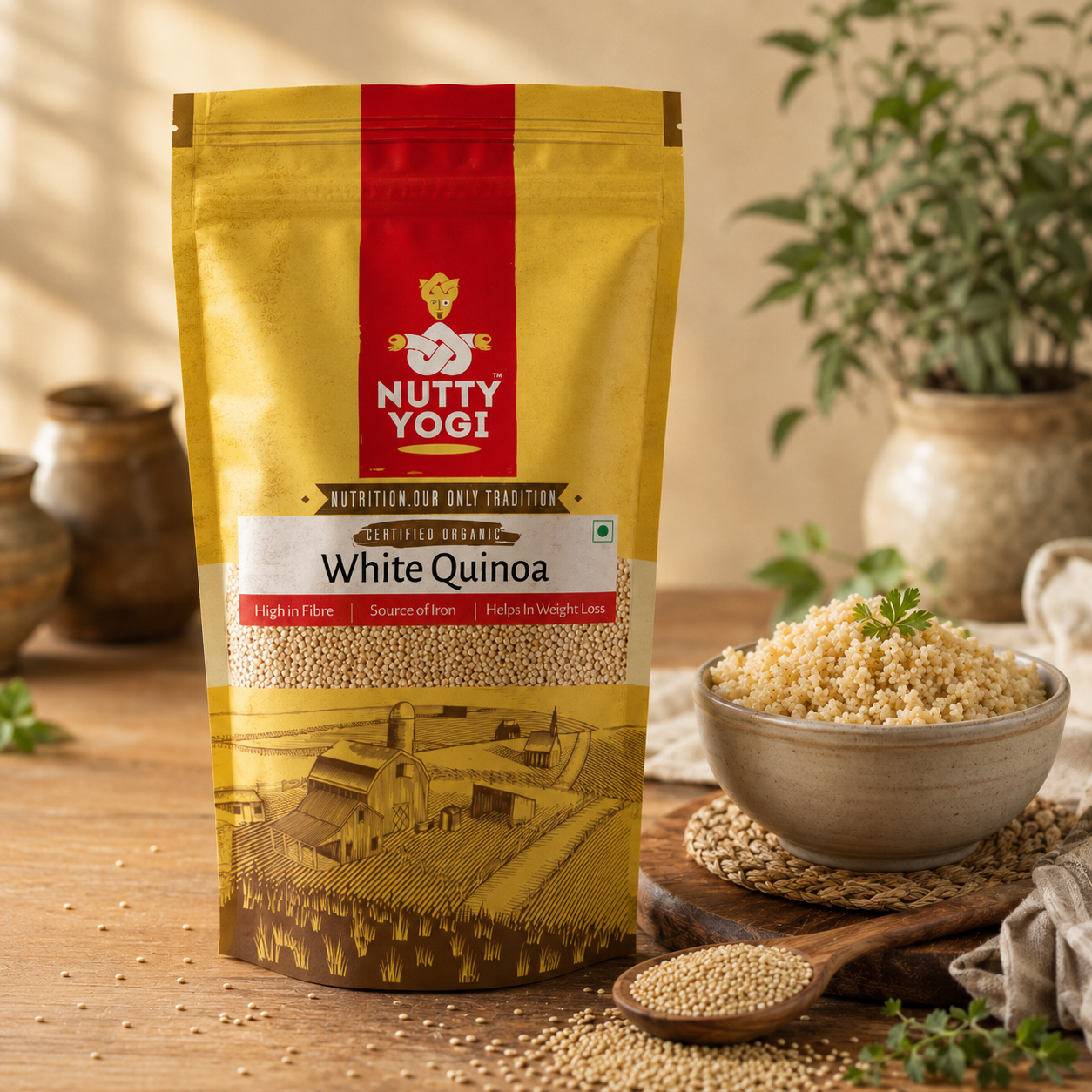 A stand-up pouch of Nutty Yogi White Quinoa set on a wooden table with a bowl of cooked quinoa, a spoon of loose grains, and potted plants in the background.