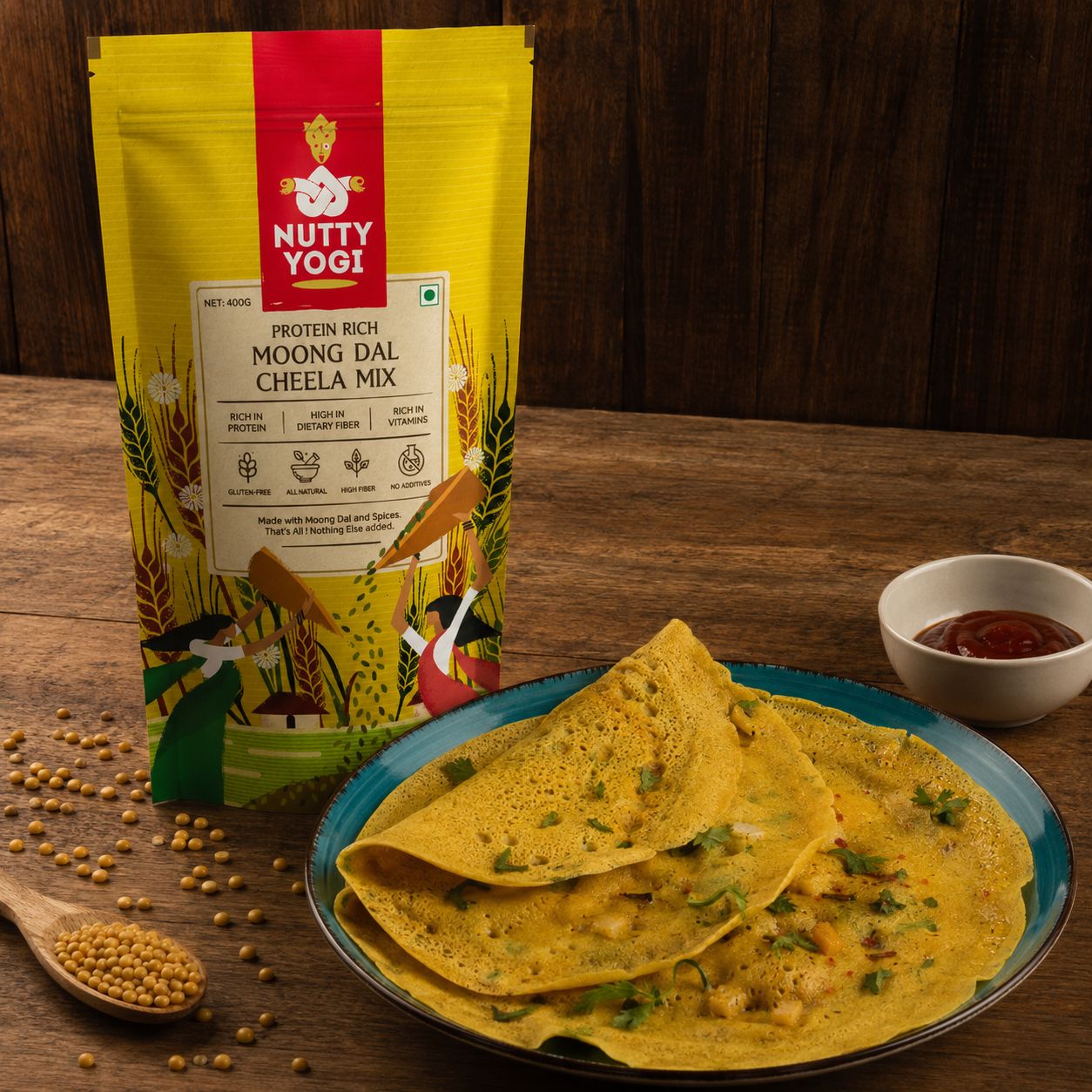 Nutty Yogi Protein Rich Moong Dal Cheela Mix displayed beside freshly made moong dal cheelas on a plate with ketchup, highlighting a wholesome, protein-rich breakfast.
