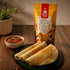 Nutty Yogi Healthy Multimillet Cheela Mix pouch served with freshly made cheelas and chutney on a wooden table.
