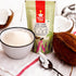 A pouch of Nutty Yogi Low Carb Keto Flour stands on a white cloth beside a bowl filled with white flour, a spoon with coconut, and whole/coconut halves, suggesting ingredients for keto nutrition.
