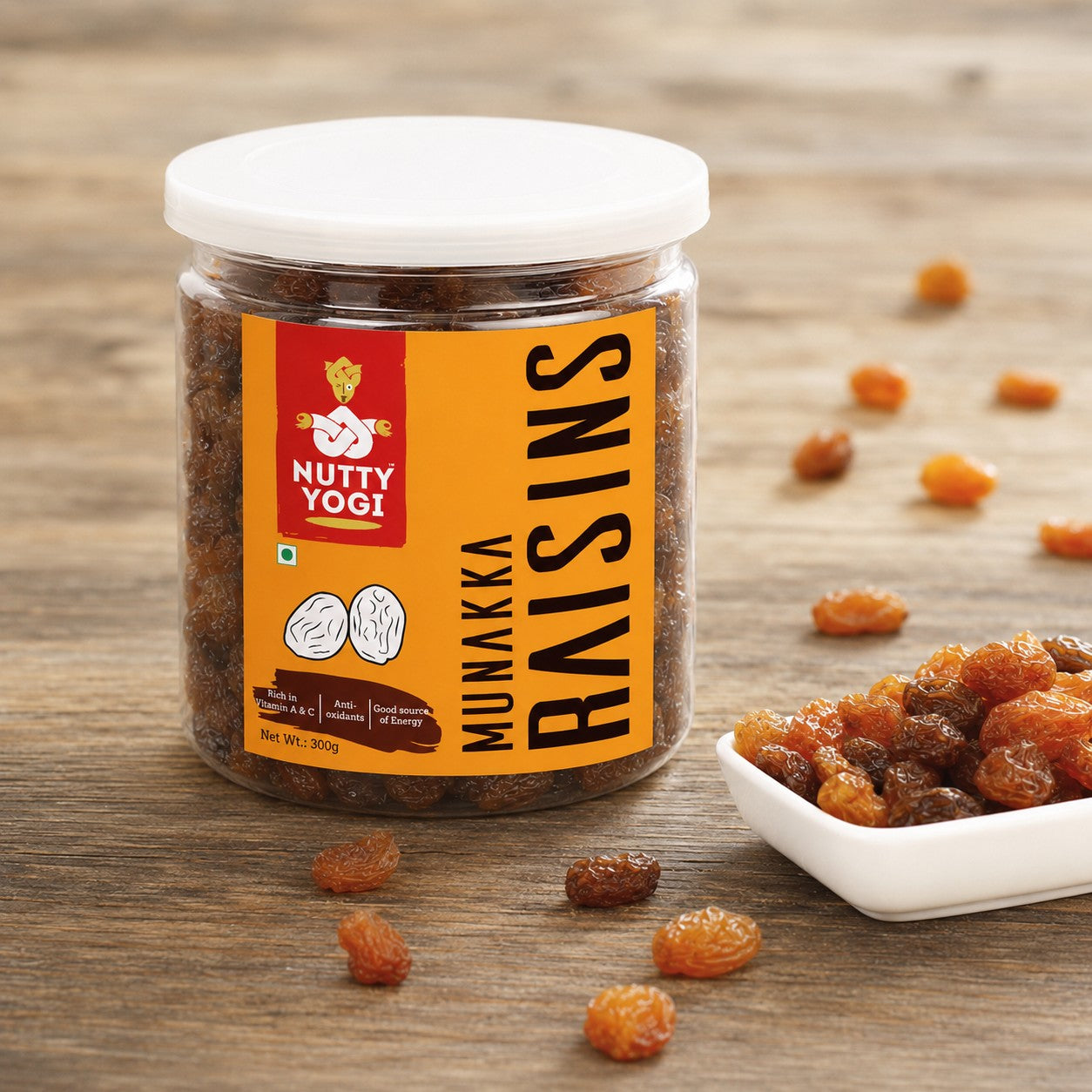 Nutty Yogi Munakka Raisins jar with premium dried raisins displayed on a wooden surface with a bowl of raisins
