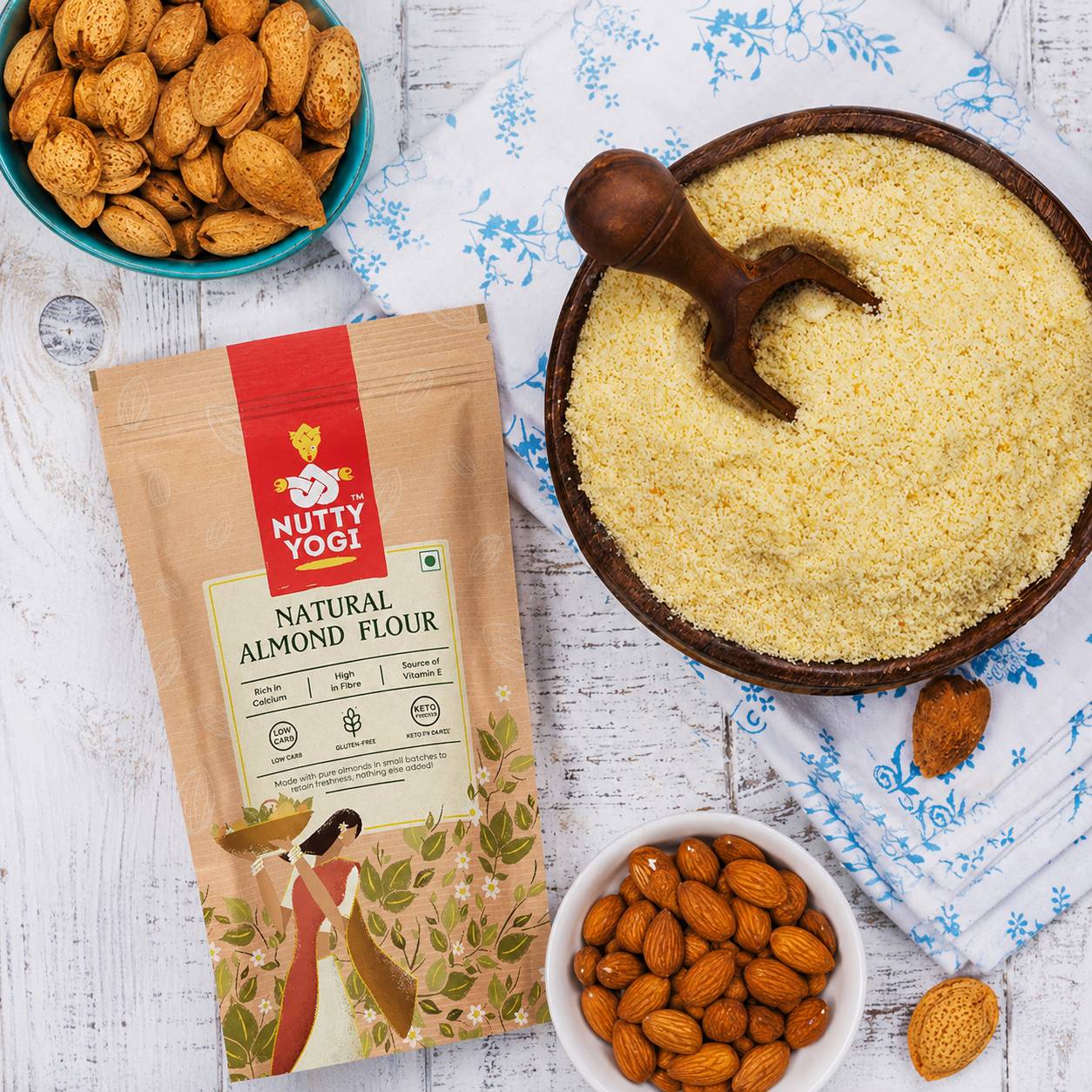 Nutty Yogi Natural Almond Flour displayed beside a bowl of almond flour and whole almonds, highlighting a premium gluten-free flour made from finely ground almonds.