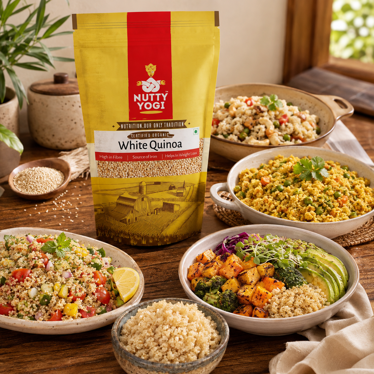 A stand-up pouch of Nutty Yogi White Quinoa flour is displayed on a wooden table surrounded by bowls and plates of prepared quinoa dishes, with loose quinoa in a spoon and bowl. The scene is styled in a warm kitchen or dining environment with plants and natural light.