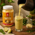 Power Protein Sattu being poured into a glass with a jar of Nutty Yogi Power Protein Sattu.